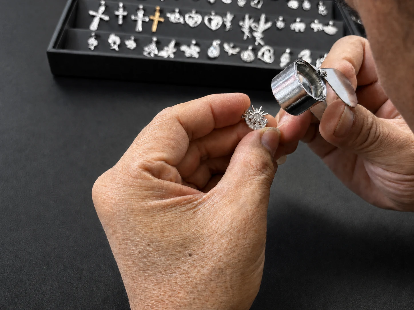 Final quality inspection of a silver pendant with a loupe